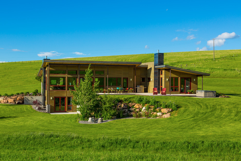 Modernes Haus mit Mix-Fassade, brauner Fassadenfarbe und Flachdach in Sonstige