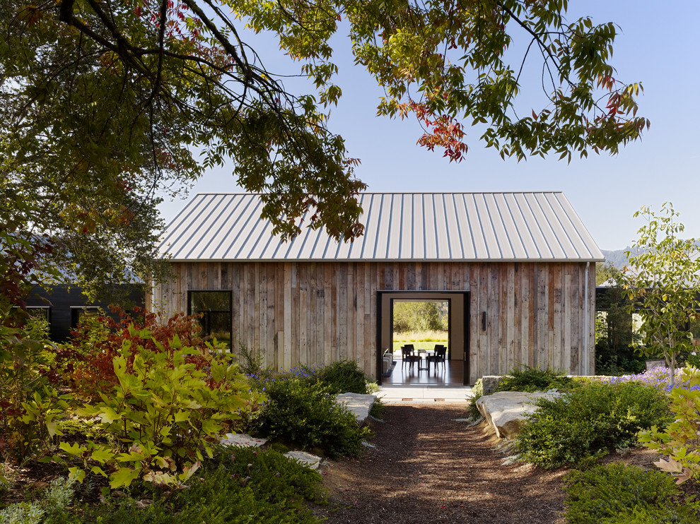 Idee per la facciata di una casa country a un piano con rivestimento in legno e tetto a capanna