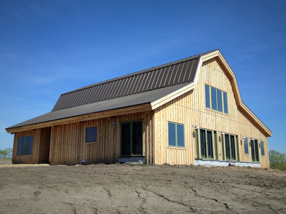 This is an example of an expansive and brown farmhouse two floor detached house in Omaha with wood cladding, a half-hip roof and a metal roof.