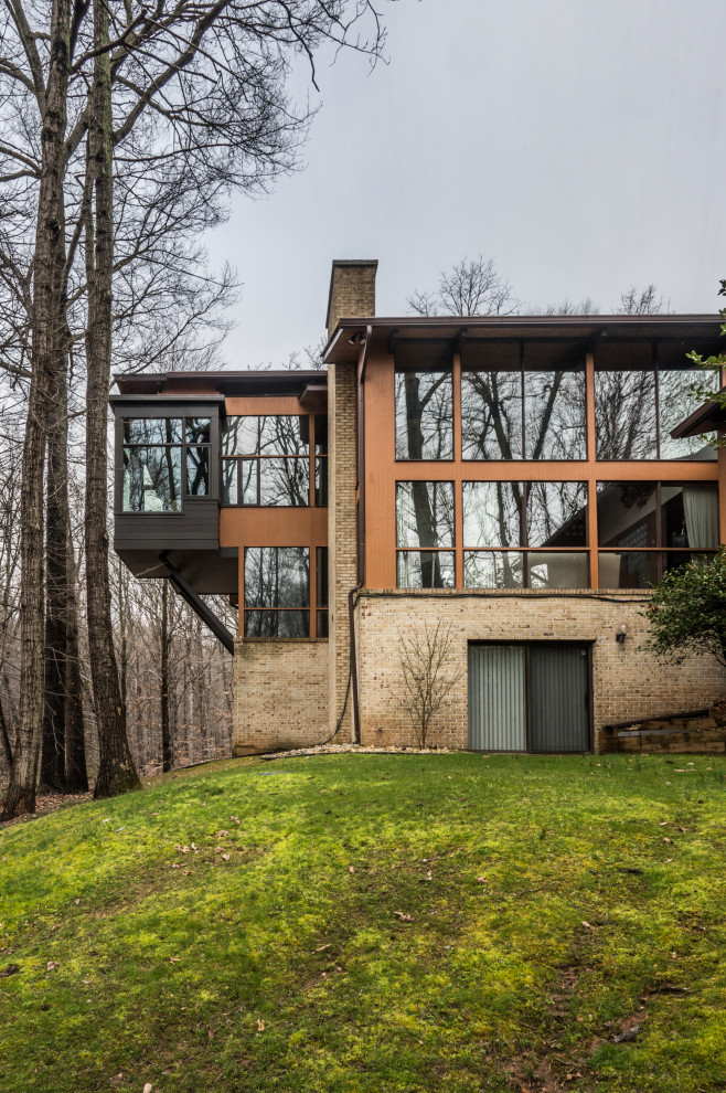 На фото: двухэтажный, коричневый частный загородный дом среднего размера в стиле неоклассика (современная классика) с комбинированной облицовкой, плоской крышей и металлической крышей