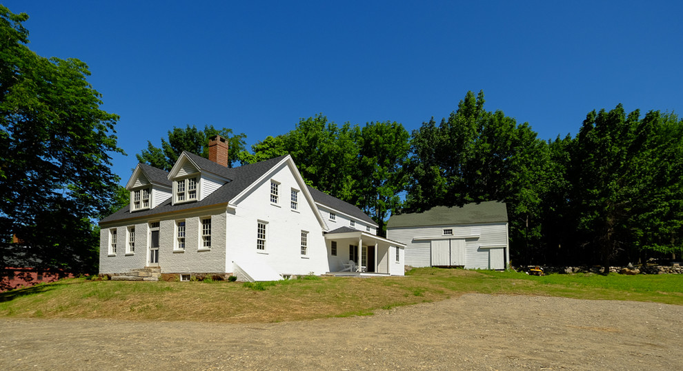 White and large farmhouse two floor brick house exterior in Portland Maine with a hip roof.