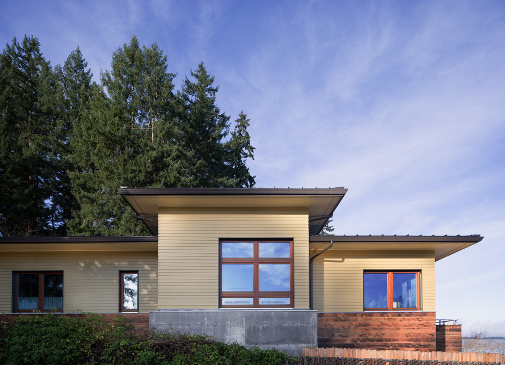 Mittelgroßes, Zweistöckiges Modernes Einfamilienhaus mit Mix-Fassade, gelber Fassadenfarbe, Pultdach und Blechdach in Seattle