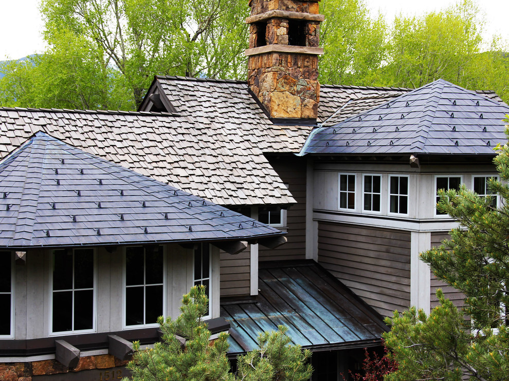 Réalisation d'une grande façade de maison grise chalet à un étage avec un revêtement mixte, un toit à deux pans et un toit en tuile.
