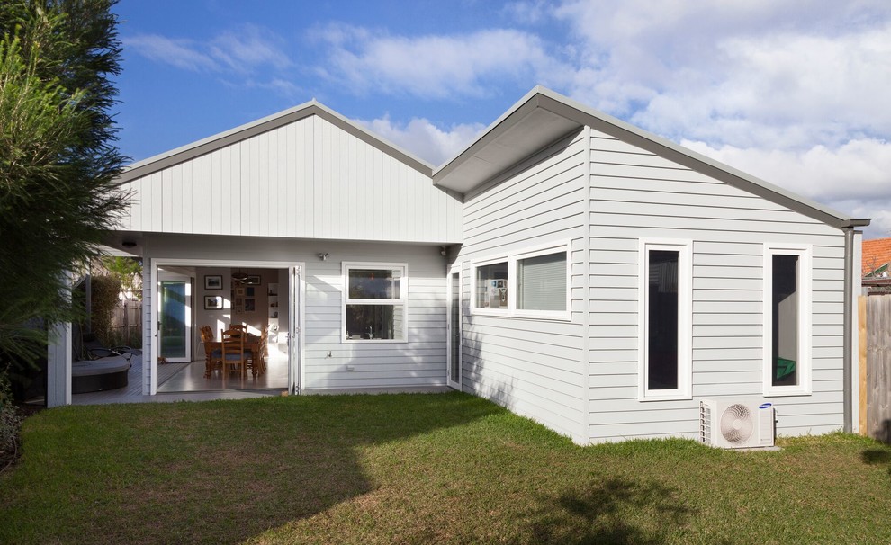 Mittelgroßes, Einstöckiges Modernes Einfamilienhaus mit Vinylfassade, weißer Fassadenfarbe, Walmdach und Blechdach in Melbourne