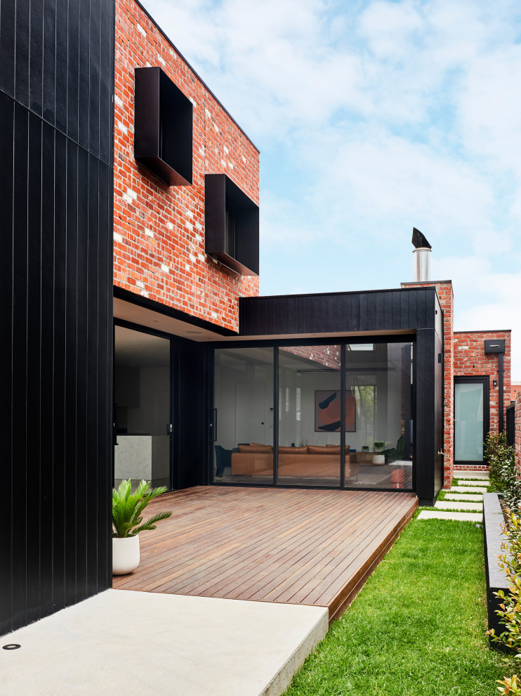 Cette photo montre une façade de maison noire moderne en panneau de béton fibré de taille moyenne et à un étage avec un toit plat et un toit en métal.