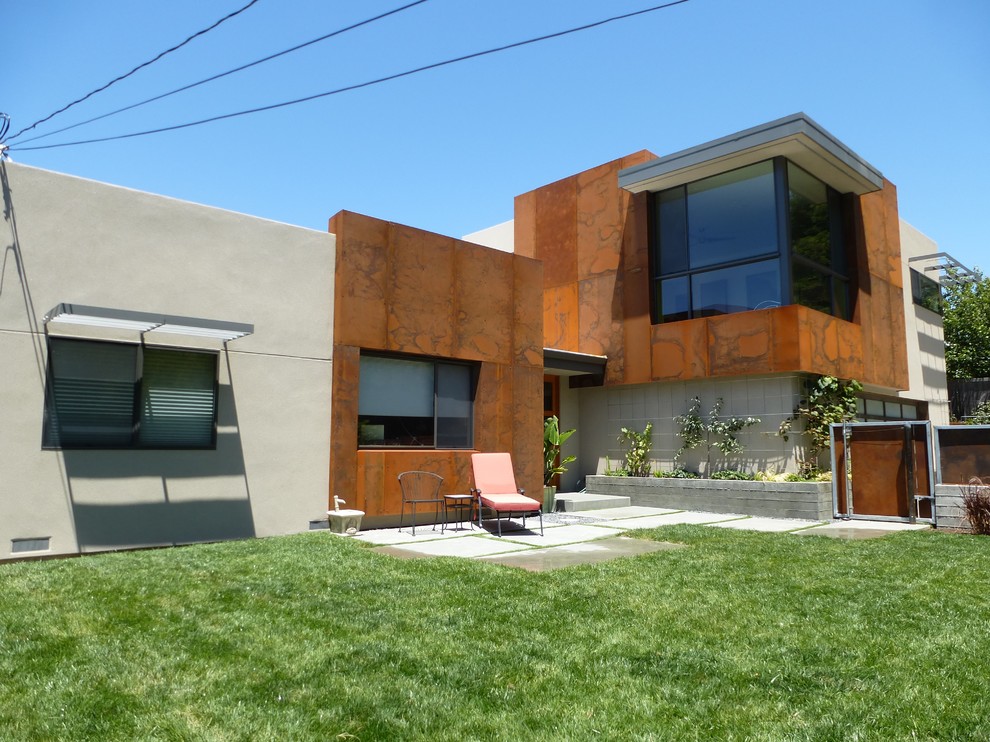 Cette image montre une façade de maison métallique et beige design de taille moyenne et à un étage avec un toit plat.