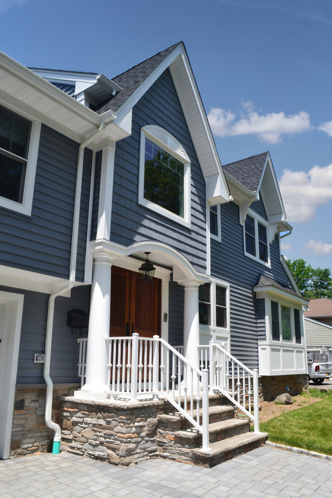 This is an example of a large and blue classic split-level house exterior in New York with vinyl cladding and a pitched roof.