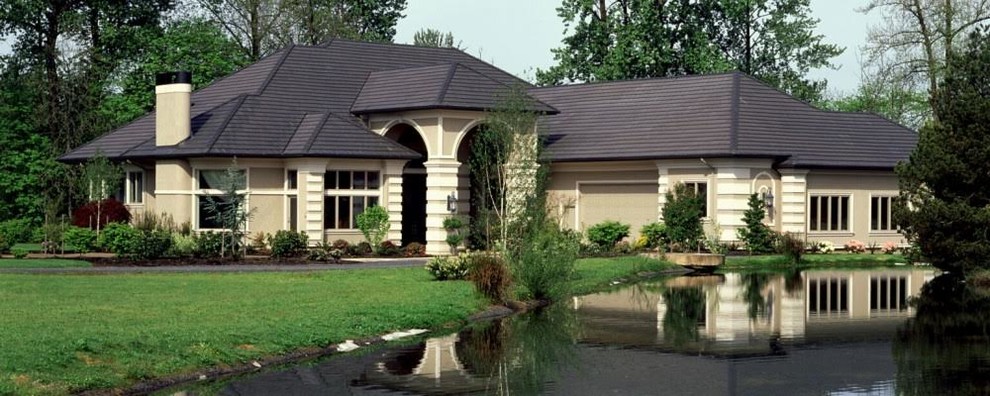 Пример оригинального дизайна: одноэтажный, бежевый, большой частный загородный дом в современном стиле с облицовкой из цементной штукатурки, двускатной крышей и черепичной крышей