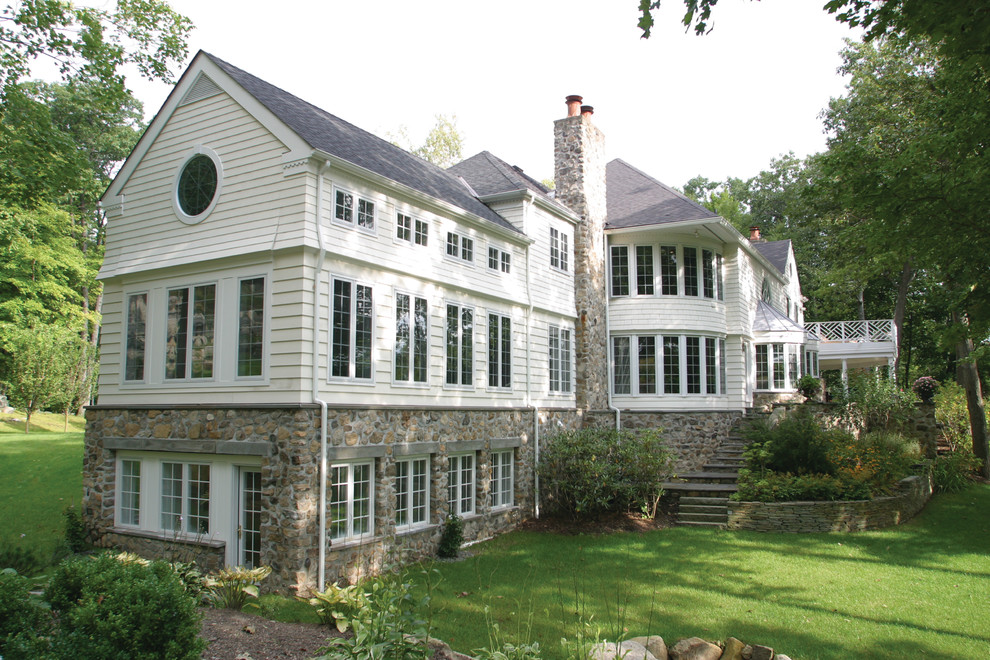 Immagine della facciata di una casa ampia bianca american style a tre piani con rivestimento in vinile e tetto a capanna
