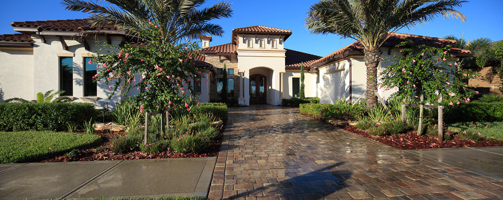This is an example of an expansive and white mediterranean bungalow render detached house in Orlando with a tiled roof.