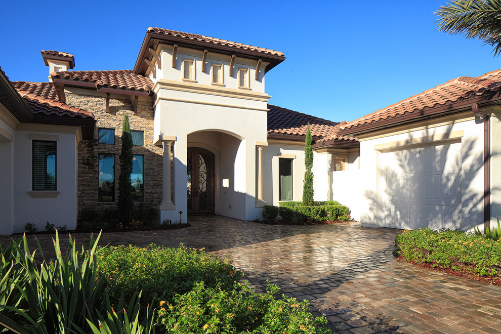 Expansive and white mediterranean bungalow render detached house in Orlando with a tiled roof.