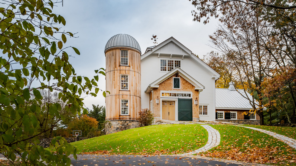 Immagine della villa multicolore country a due piani con rivestimenti misti, tetto a capanna e copertura in metallo o lamiera