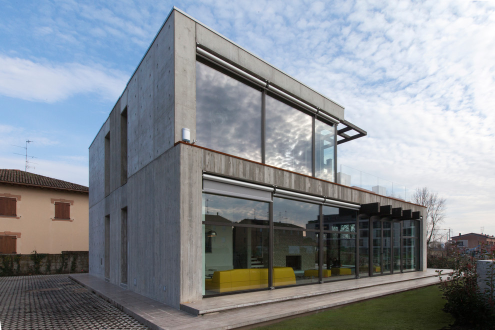 Cette image montre une façade de maison grise urbaine en béton de taille moyenne et à un étage avec un toit plat.