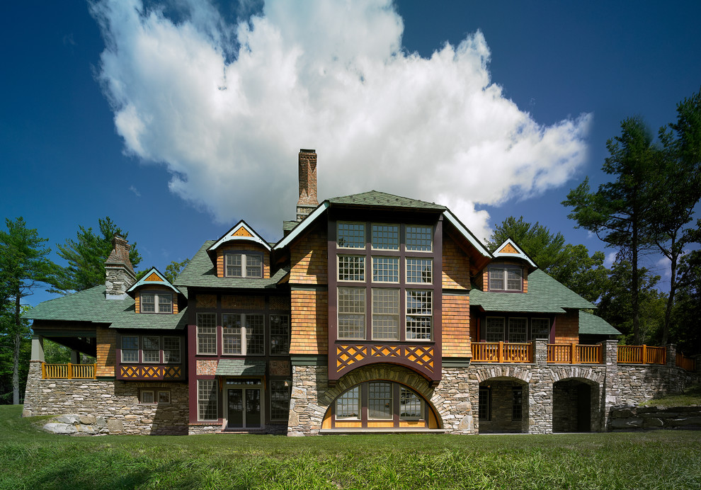 На фото: трехэтажный дом в стиле кантри с полувальмовой крышей и комбинированной облицовкой с