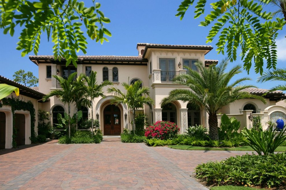 Large mediterranean beige two-story stucco house exterior idea in Miami with a hip roof and a tile roof