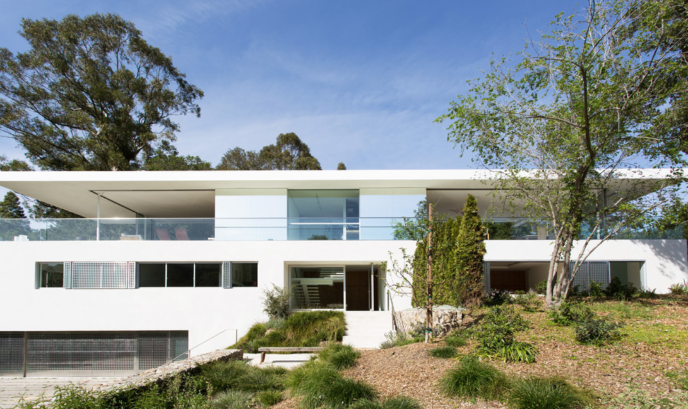 Modelo de fachada blanca minimalista de tres plantas con tejado plano