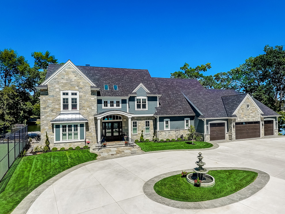 This is an example of an expansive and gey beach style two floor detached house in Milwaukee with stone cladding, a pitched roof and a shingle roof.