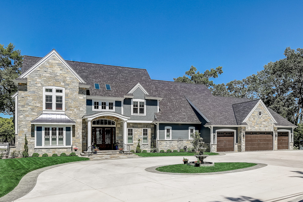 Huge coastal gray two-story stone exterior home idea in Milwaukee with a shingle roof