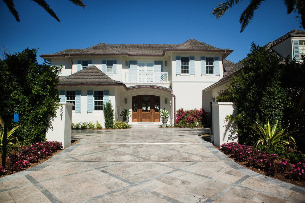 Example of a large island style white two-story stucco house exterior design in Miami with a hip roof and a shingle roof
