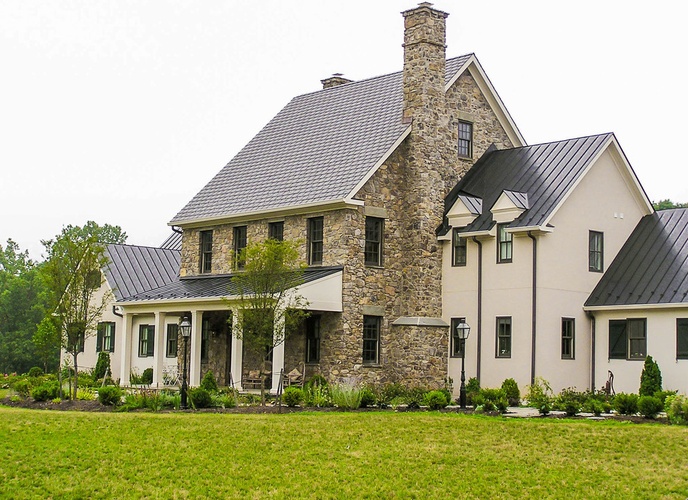 Aménagement d'une grande façade de maison beige campagne à un étage avec un revêtement mixte et un toit à deux pans.