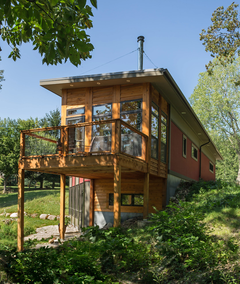 Cette image montre une petite façade de maison rouge design à un étage avec un revêtement mixte et un toit en appentis.