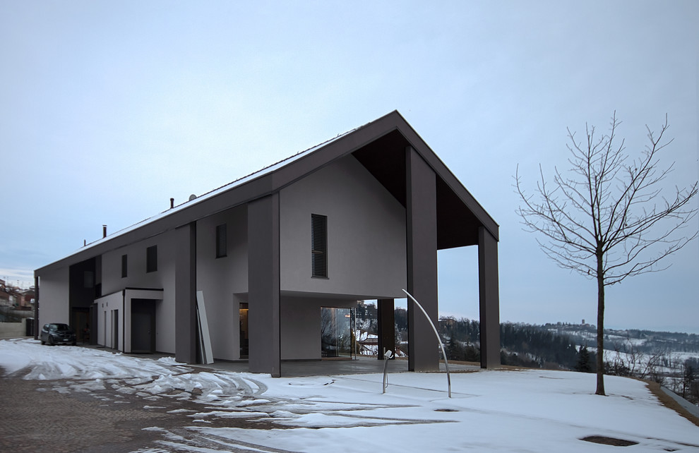 Inspiration pour une grande façade de maison design en stuc à un étage avec un toit à deux pans.