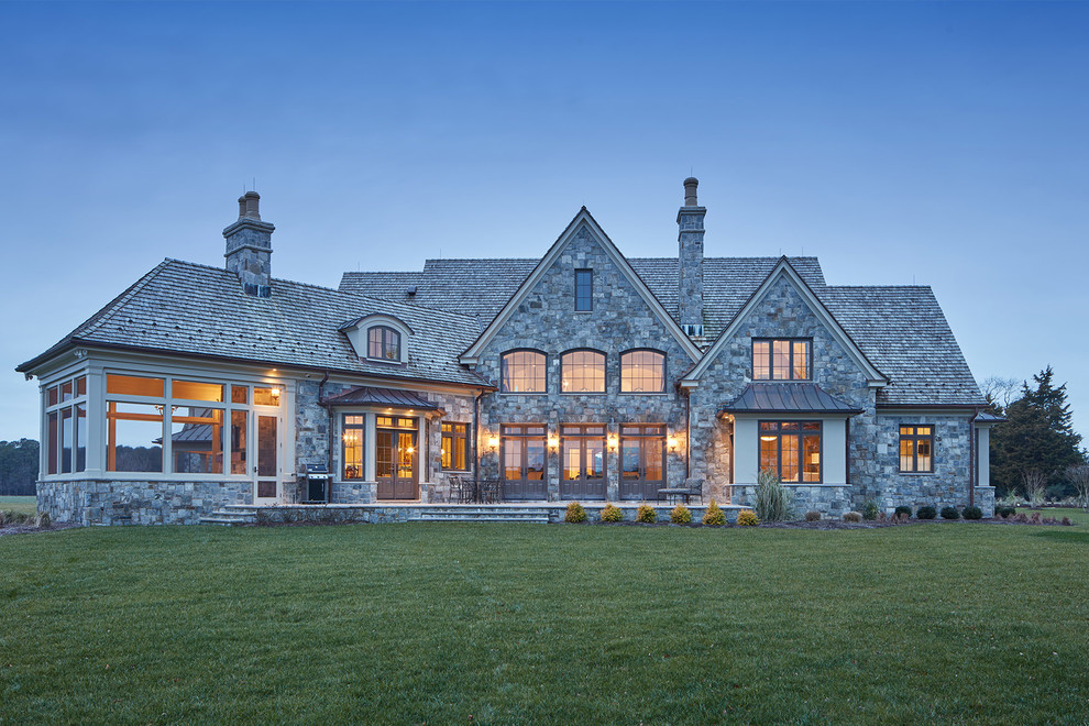 Diseño de fachada de casa gris tradicional con revestimiento de piedra, tejado a dos aguas y tejado de teja de madera