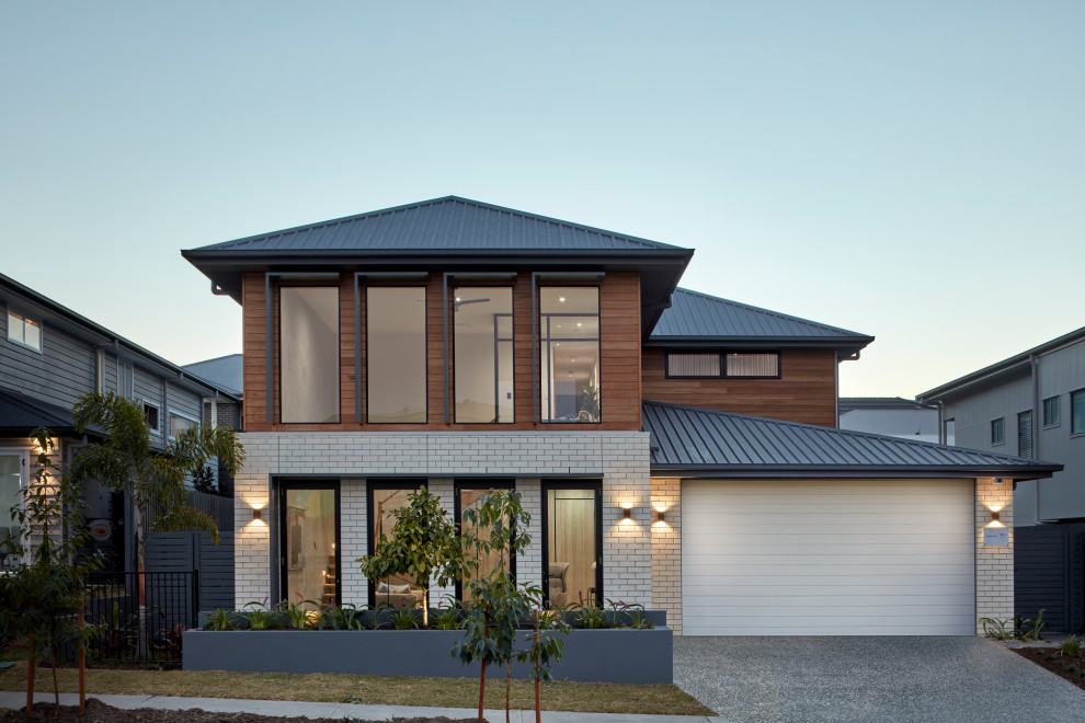 Свежая идея для дизайна: двухэтажный, кирпичный, разноцветный частный загородный дом в современном стиле с вальмовой крышей и металлической крышей - отличное фото интерьера