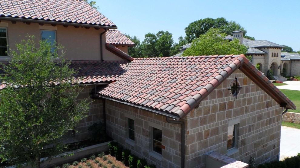 Idée de décoration pour une grande façade de maison marron méditerranéenne en pierre à un étage avec un toit à quatre pans.