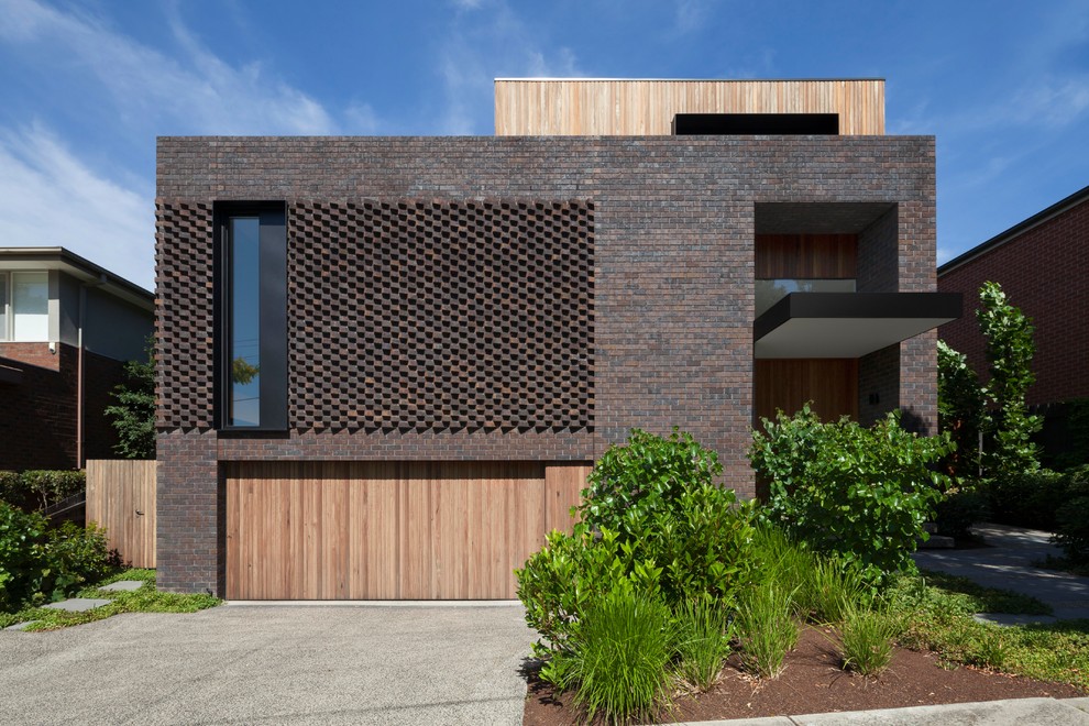 Foto på ett funkis brunt hus i flera nivåer, med blandad fasad och platt tak