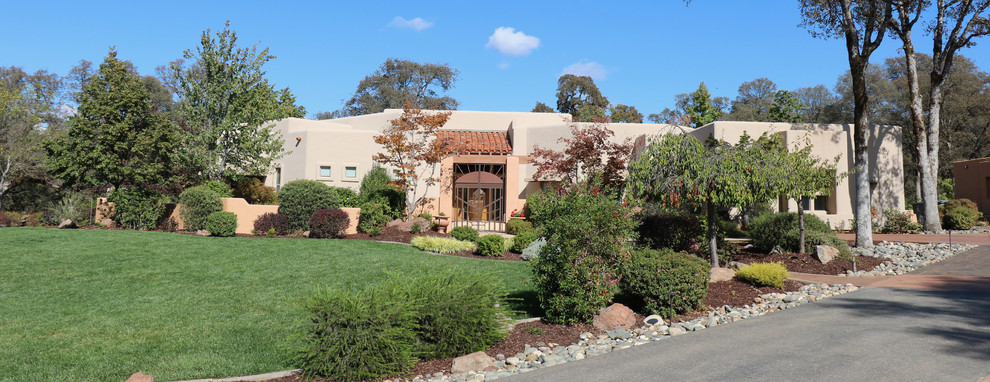 Immagine della facciata di una casa grande beige american style a un piano con rivestimento in stucco e tetto piano
