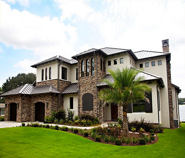 This is an example of a medium sized and beige mediterranean two floor detached house in Orlando with mixed cladding, a hip roof and a metal roof.