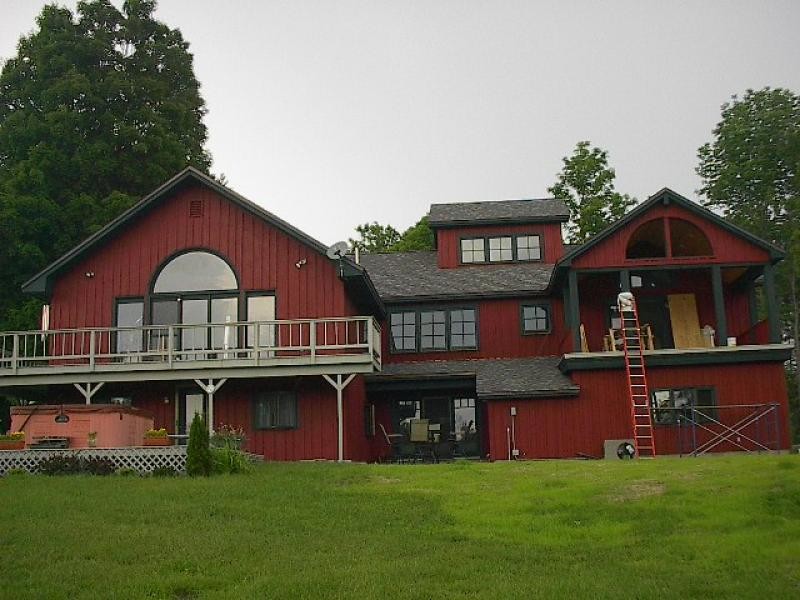 Foto della facciata di una casa grande rossa country a due piani con rivestimento in legno