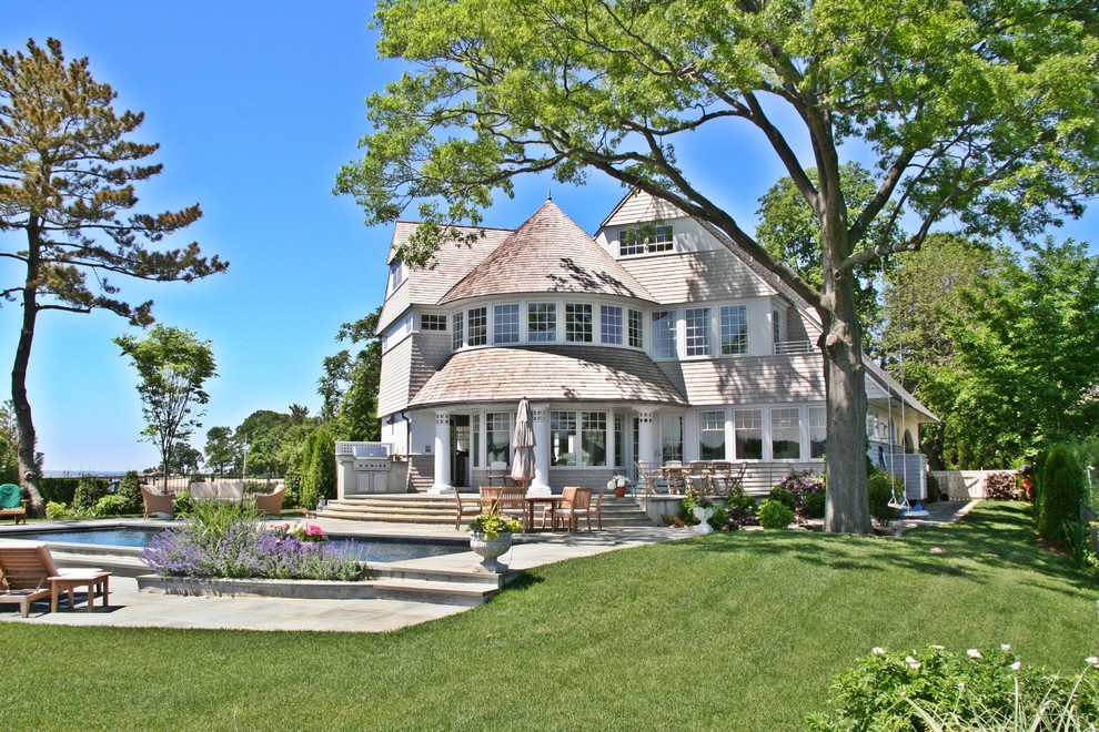 Пример оригинального дизайна: трехэтажный, серый частный загородный дом среднего размера в викторианском стиле с облицовкой из винила, двускатной крышей и крышей из гибкой черепицы