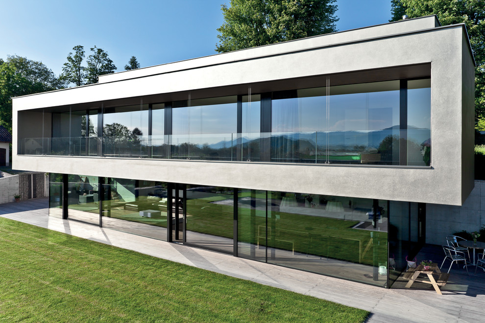 Inspiration för ett stort funkis grått hus, med två våningar, glasfasad och platt tak