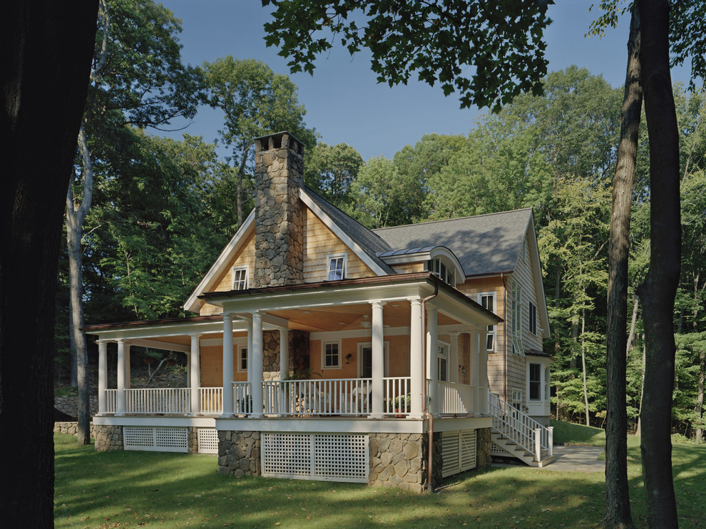 Пример оригинального дизайна: большой, желтый частный загородный дом в стиле шебби-шик с разными уровнями, облицовкой из камня и полувальмовой крышей