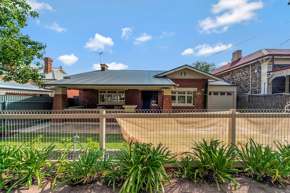 Elegant red one-story brick exterior home photo in Adelaide with a metal roof