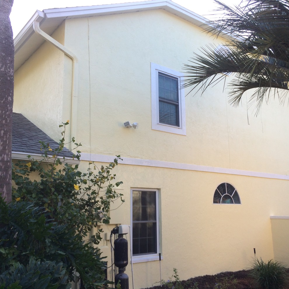 Inspiration for a large and yellow contemporary two floor render house exterior in Tampa.