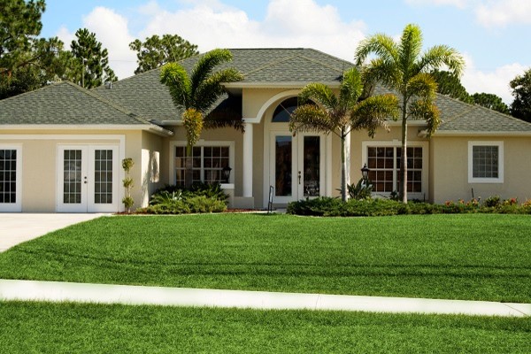 This is an example of an expansive and beige classic split-level render house exterior in Tampa.
