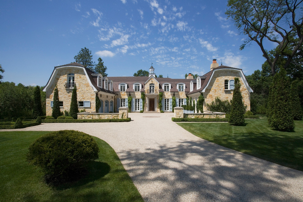 Immagine della villa ampia beige classica a tre piani con rivestimento in mattoni, tetto a mansarda e copertura in tegole