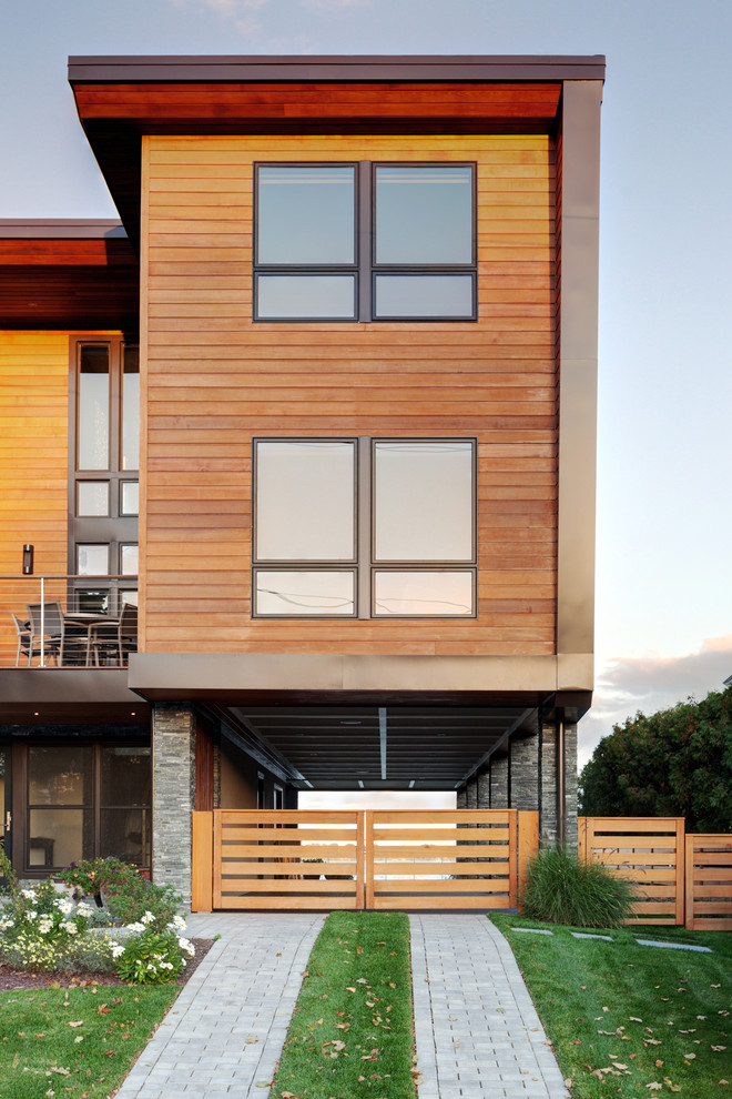 Immagine della facciata di una casa contemporanea a tre piani con rivestimento in legno e tetto piano