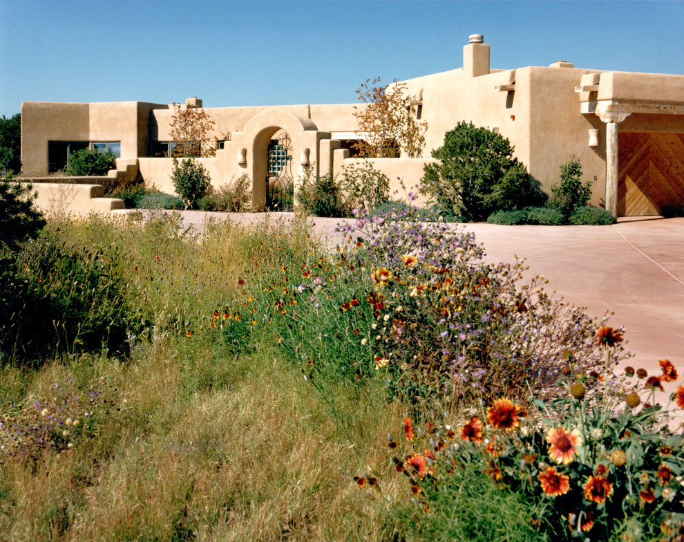 Cette image montre une grande façade de maison beige sud-ouest américain en stuc de plain-pied.