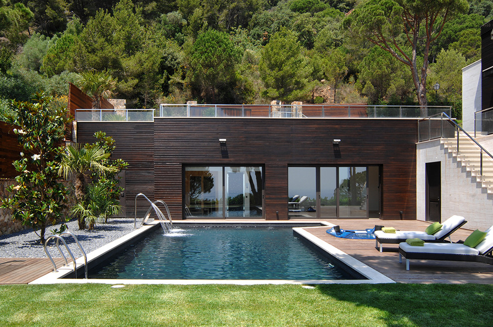 Photo of a large and brown contemporary bungalow house exterior in Barcelona with wood cladding and a flat roof.