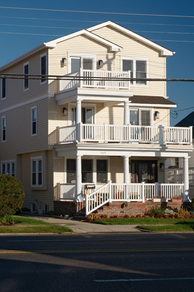 Mittelgroßes, Dreistöckiges Maritimes Haus mit Vinylfassade, gelber Fassadenfarbe und Satteldach in Philadelphia