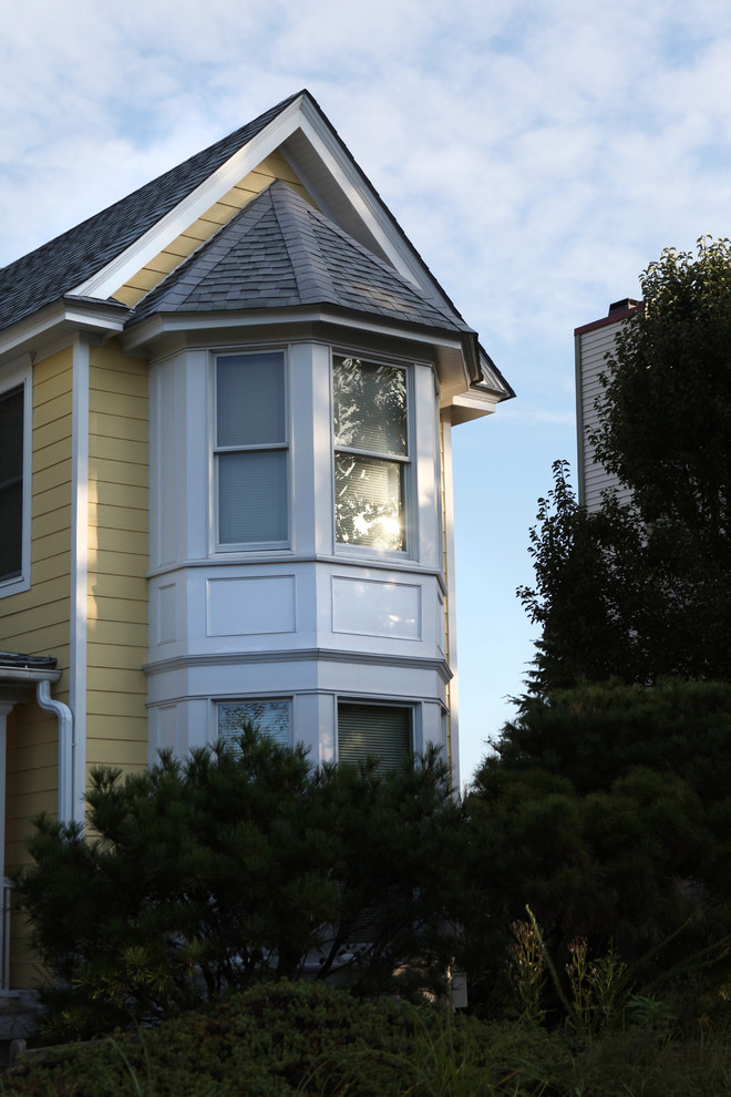 Стильный дизайн: двухэтажный, желтый дом среднего размера в классическом стиле с облицовкой из ЦСП и вальмовой крышей - последний тренд