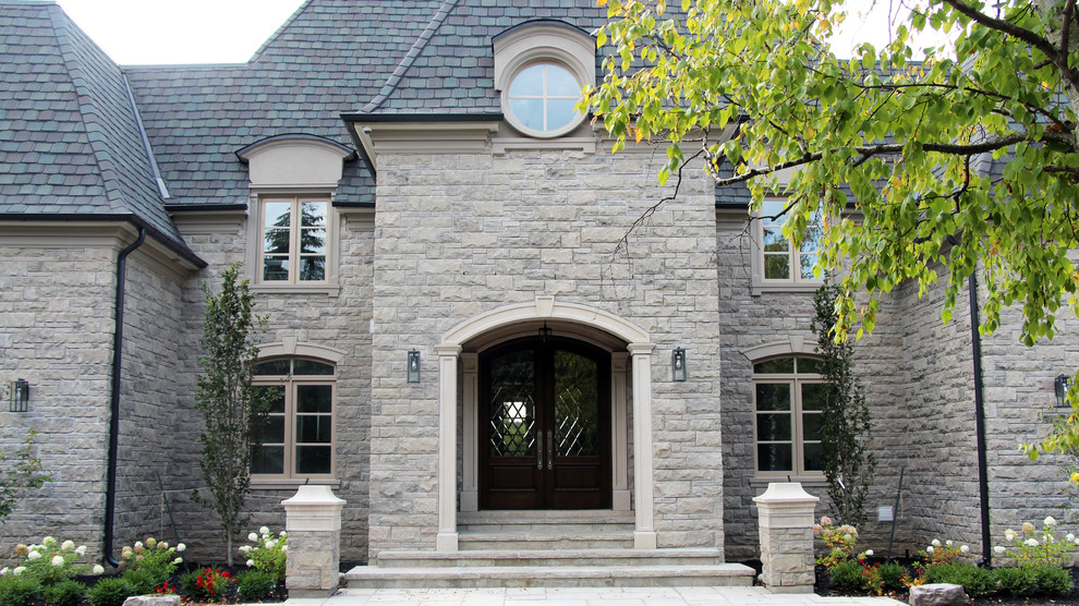 Imagen de fachada de casa beige de estilo americano grande de tres plantas con revestimiento de piedra, tejado a doble faldón y tejado de teja de madera