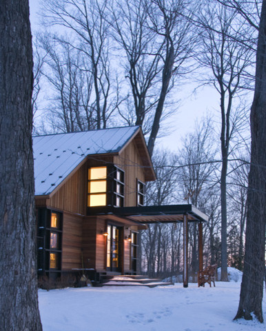 Immagine della villa grande contemporanea a tre piani con rivestimento in legno, tetto a capanna e copertura in metallo o lamiera