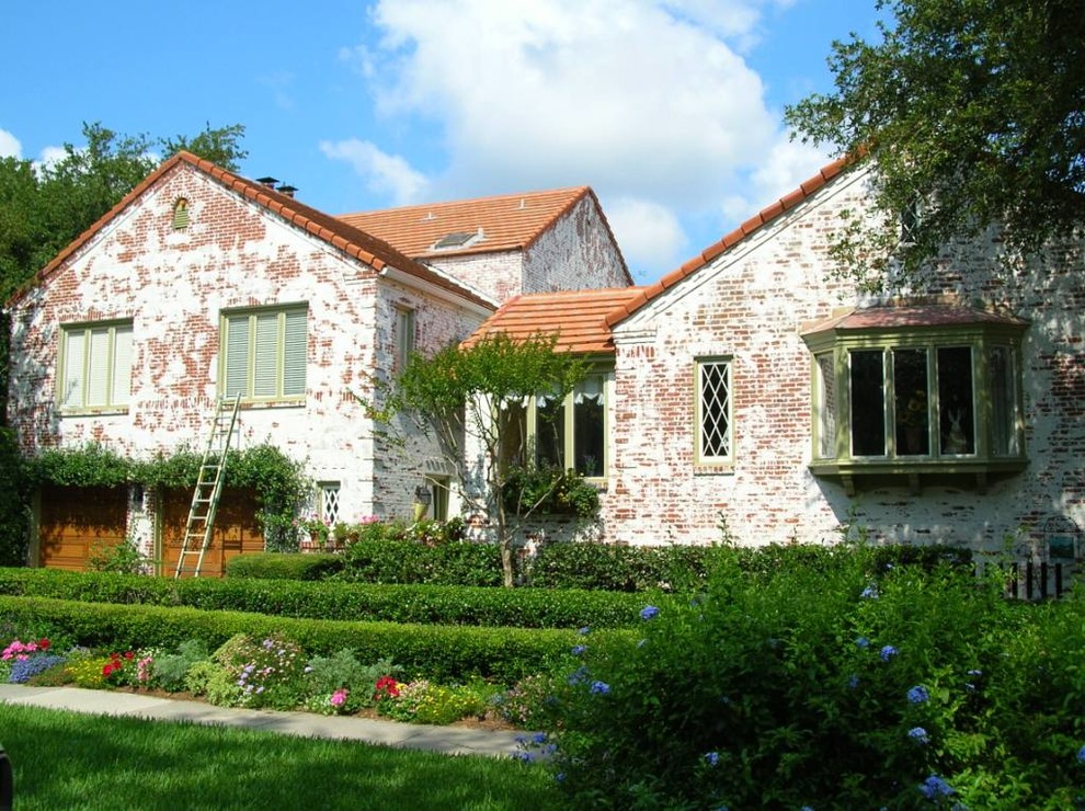 Immagine della villa grande multicolore rustica a due piani con rivestimento in mattoni, tetto a capanna e copertura in tegole