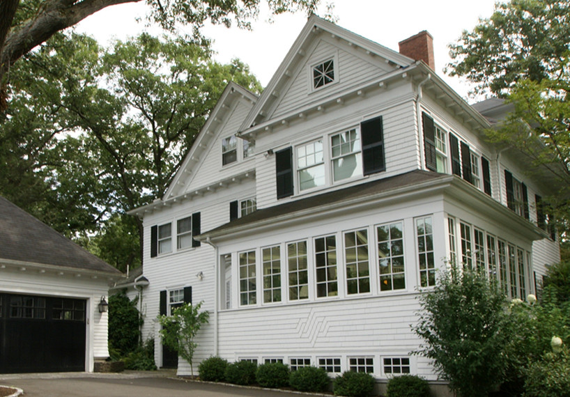 Modelo de fachada blanca clásica de tamaño medio de tres plantas con revestimiento de madera y tejado a dos aguas
