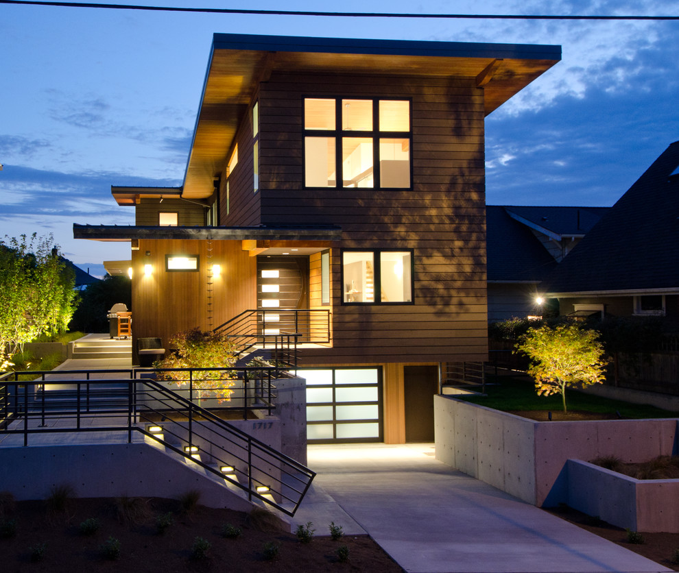Esempio della facciata di una casa grande marrone contemporanea a tre piani con rivestimento in legno e tetto piano